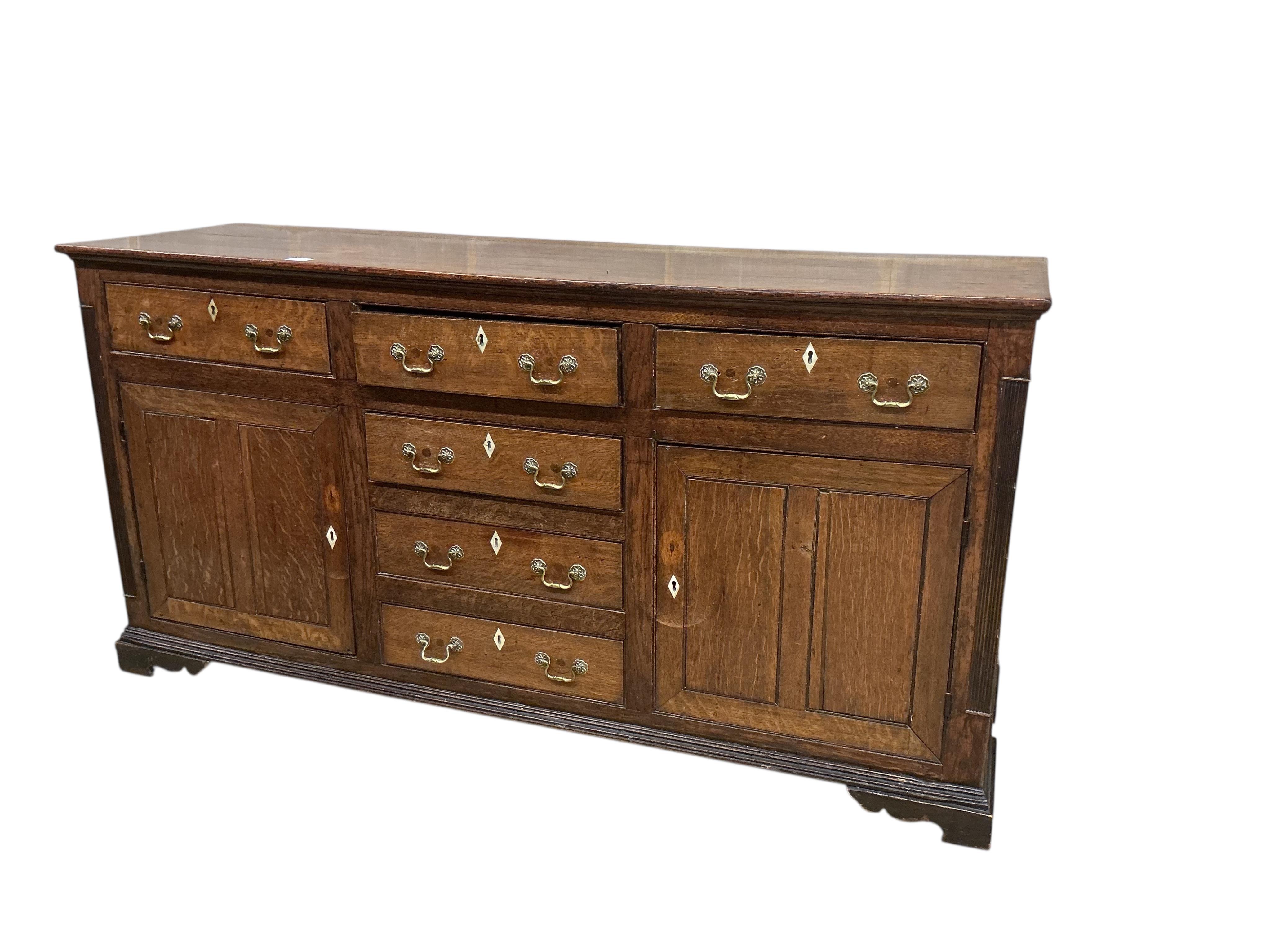 A George III oak low dresser base, later replacement handles, width 178cm, depth 54cm, height 91cm